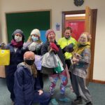 A group of 6 students smiling with their Winter Warmer goodies - they all have woolly hats on or are holding hats. Two of the students are holding SRUCSA branded paper bags. Some are wearing face coverings.