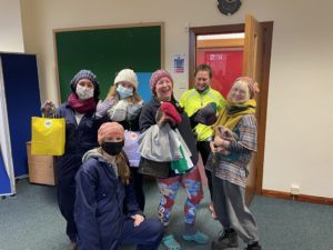 A group of 6 students smiling with their Winter Warmer goodies - they all have woolly hats on or are holding hats. Two of the students are holding SRUCSA branded paper bags. Some are wearing face coverings.
